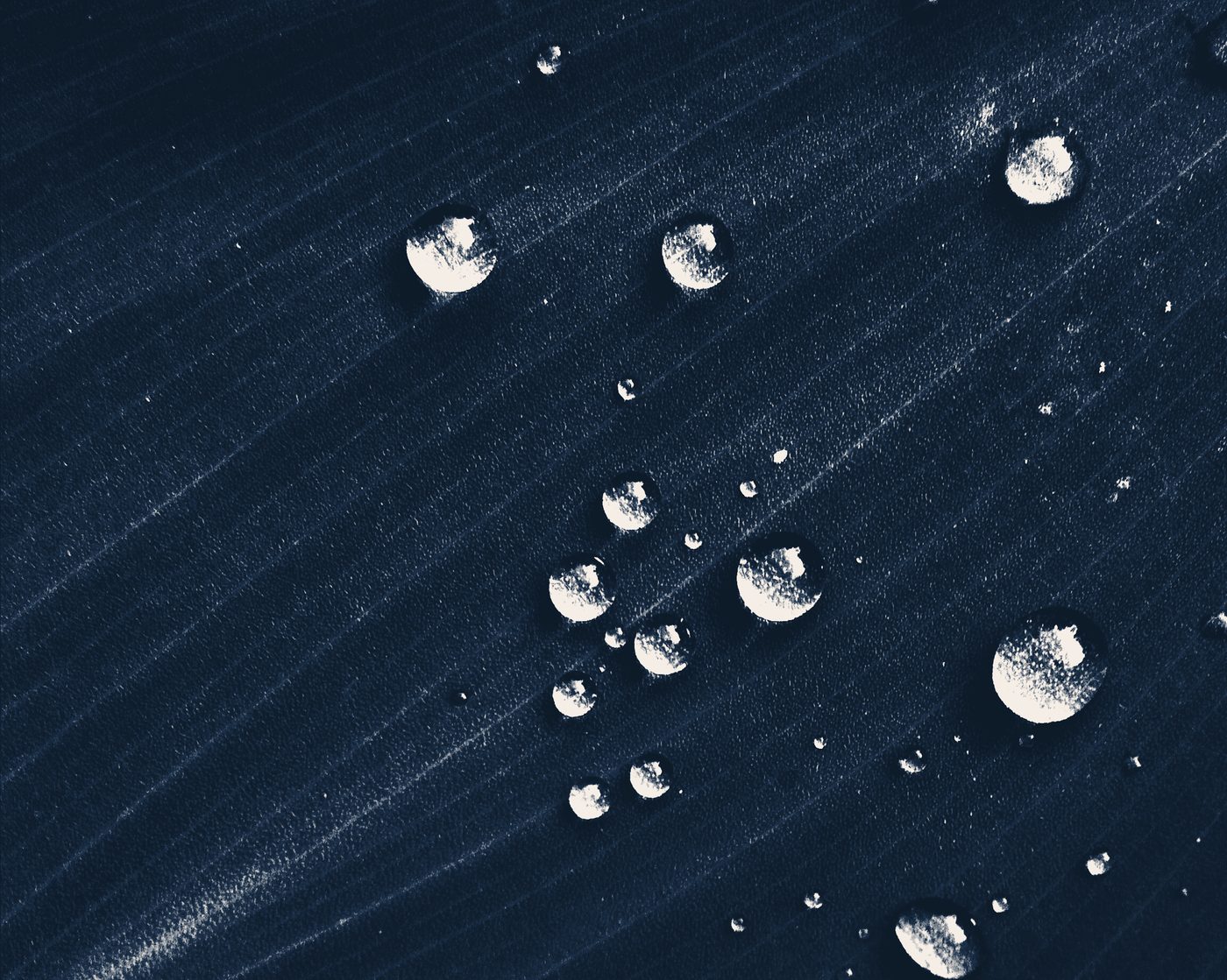 Water droplets beading on a dark surface, close up